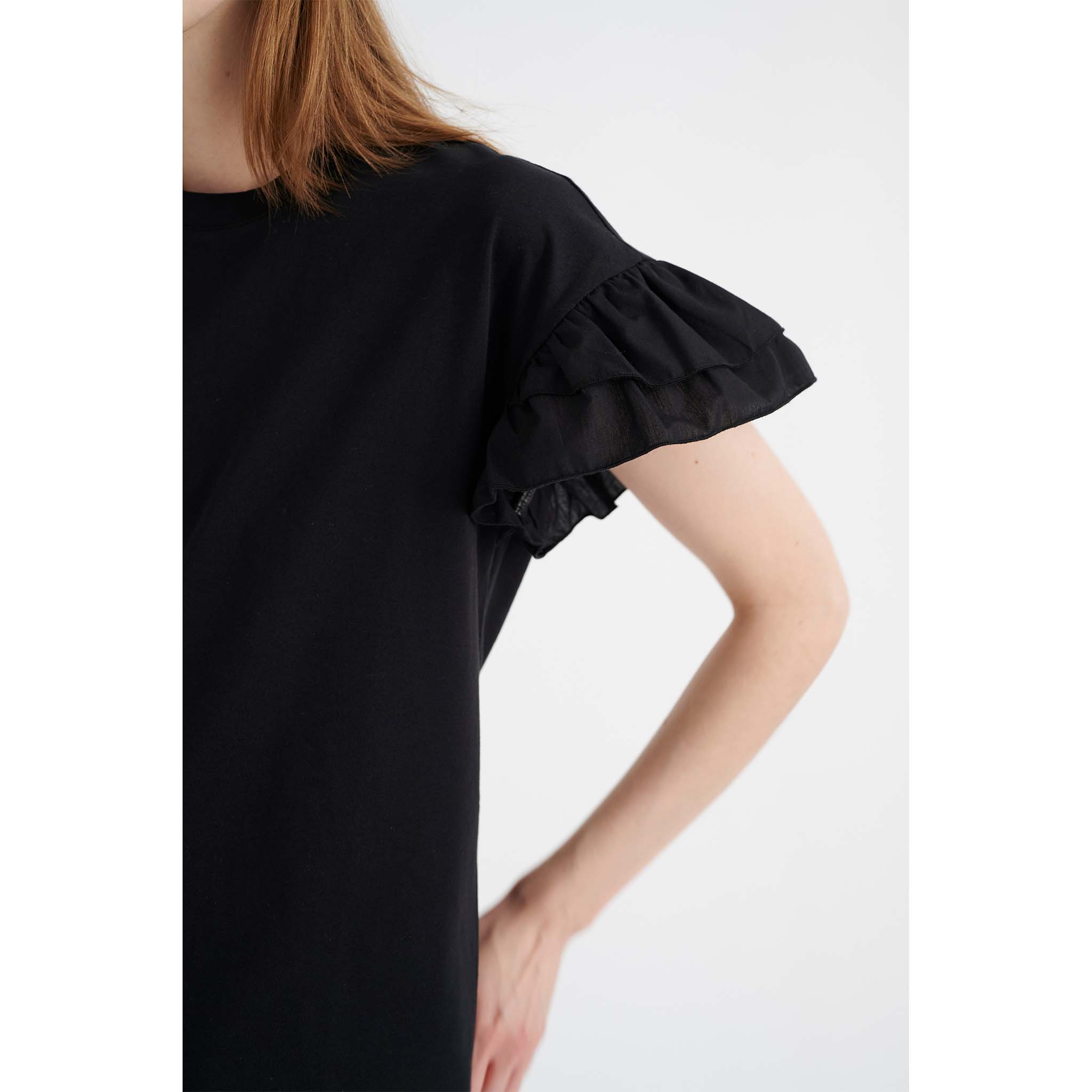 In Wear, musta t-paita, jossa on frilla-hihat. Lähikuva mallin päällä.