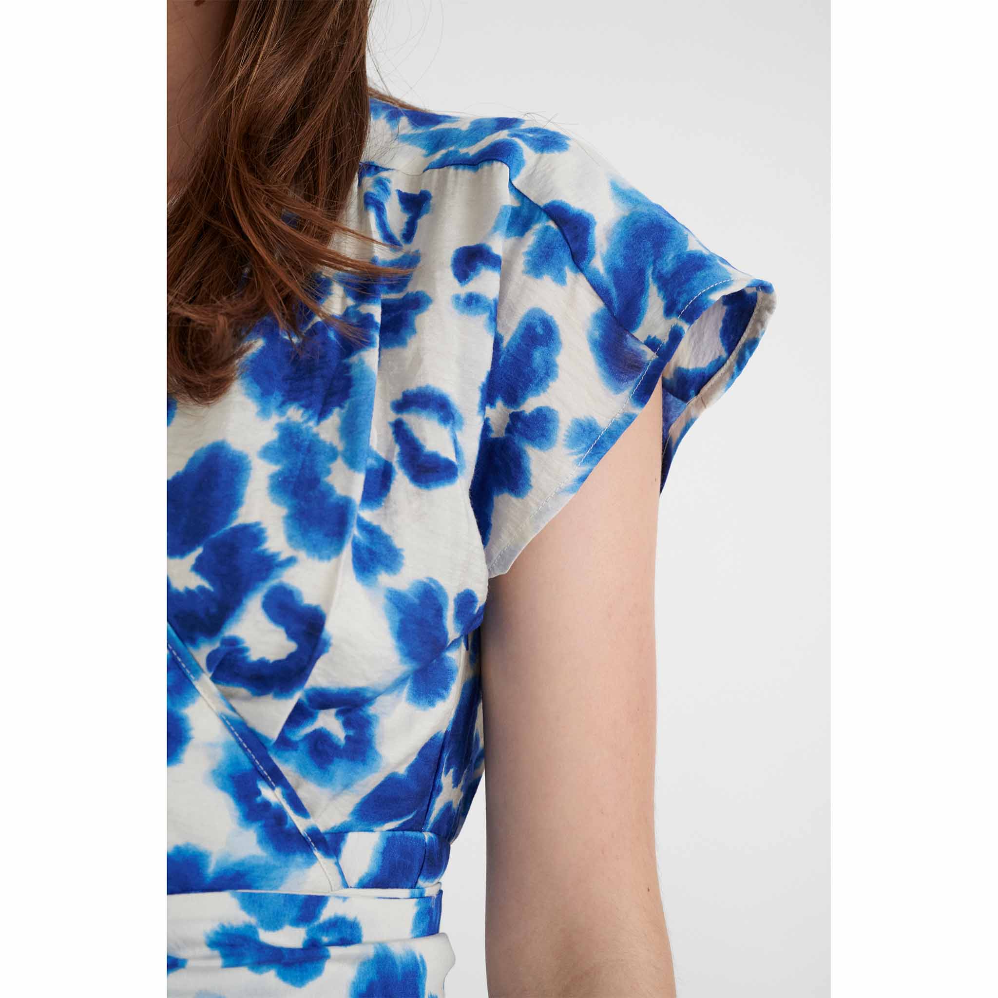 In Wearin kietaisumekko. Vaalealla pohjalla voimakkaan sinisävyisiä kukka-aiheita. Lähikuva mallin päällä.