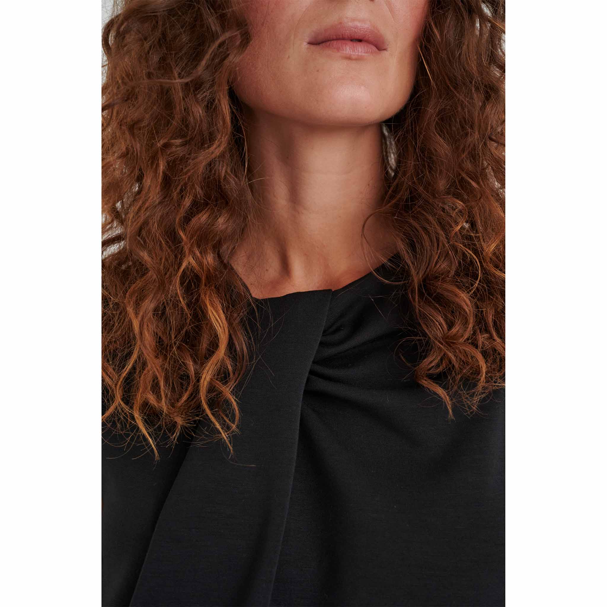 In Wear, naisten musta hihaton pusero. Edessä epäsymmetrinen laskos ja poimutusta. Lähikuva mallin päällä.